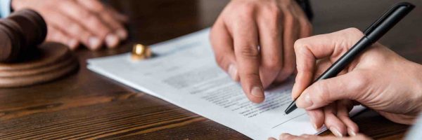 Richterhammer Anwaltshände die auf Scheidungspapiere zeigen Eheringe Frau die unterzeichnet